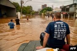FILE - A volunteer group of off-road drivers helps rescue people in flood-hit areas in Porto Alegre, Rio Grande do Sul State, Brazil, on May 4, 2024. (Photo by Carlos Fabal / AFP)