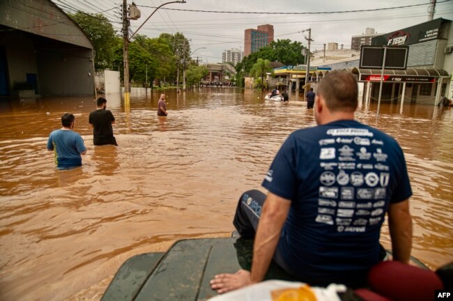 FILE - A volunteer group of off-road drivers helps rescue people in flood-hit areas in Porto Alegre, Rio Grande do Sul State, Brazil, on May 4, 2024. (Photo by Carlos Fabal / AFP)