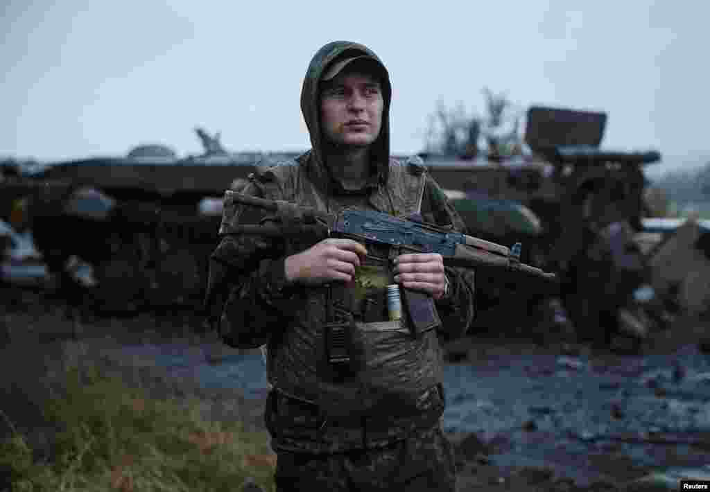 A Ukrainian soldier stands near a destroyed military vehicle that belonged to pro-Russian separatists just outside the eastern Ukrainian city of Slovyansk, July 7, 2014.