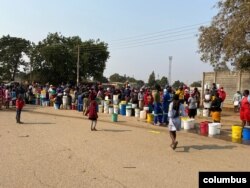 People in Harare forget about social distance to contain coronavirus and get crowded while waiting for free water deliveries from well wishers like Clean City. (Columbus Mavhunga/VOA)