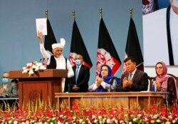 Afghan President Ashraf Ghani holds up the resolution on the last day of an Afghan Loya Jirga or traditional council, in Kabul, Afghanistan, Aug. 9, 2020. The council concluded Sunday with hundreds of delegates agreeing to free 400 Taliban members.