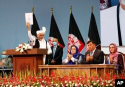 Afghan President Ashraf Ghani holds up the resolution on the last day of an Afghan Loya Jirga or traditional council, in Kabul, Afghanistan, Aug. 9, 2020. The council concluded Sunday with hundreds of delegates agreeing to free 400 Taliban members.