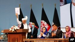 Afghan President Ashraf Ghani holds up the resolution on the last day of an Afghan Loya Jirga or traditional council, in Kabul, Afghanistan, Aug. 9, 2020. 