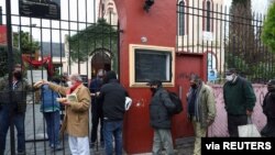 FILE - People line up to receive a ration of stew at a soup kitchen organized at the Caacupe church, during the coronavirus disease (COVID-19) outbreak, in Buenos Aires, Argentina, July 23, 2020.