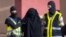 FILE - Masked Spanish police officers lead a detained woman in Melilla, Dec. 16, 2014. Arrest was part of ongoing swoop on suspected efforts to recruit women to go to Syria and Iraq to support Islamic State insurgents.