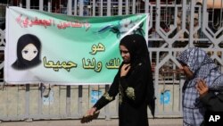 FILE - Females pass by a banner in Baghdad, Iraq, March 13, 2014. 