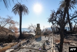 FILE - A chimney stands amid burnt trees and ashes at the remains of a house overlooking the Pacific Ocean after the Palisades fire in Malibu, California, Jan. 21, 2025.