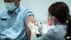 FILE - A Tokyo municipal government employee receives a shot of the Moderna COVID-19 vaccine at a vaccination center at a local government building, in Tokyo, Japan, July 1, 2021.