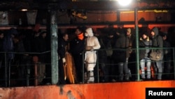 FILE - Migrants are seen on the The Blue Sky M cargo ship, carrying an estimated 900 migrants, as they arrive at the Gallipoli harbor in southern Italy, December 31, 2014.