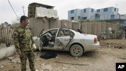 An Iraqi police commando stands next to the wreckage of a car at the site of suicide bombing in the restive city of Baquba northeast of Baghdad, 03 Mar 2010