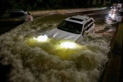 A motorist drives a car through a flooded expressway in Brooklyn, New York early on September 2, 2021, as flash flooding and record-breaking rainfall brought by the remnants of Storm Ida swept through the area.