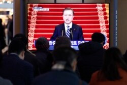 People watch a TV screen showing the live broadcast of South Korean President Moon Jae-in's New Year's speech at the Seoul Railway Station in Seoul, South Korea, Tuesday, Jan. 7, 2020.