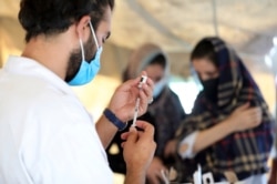 FILE - A doctor fills a syringe with the Johnson & Johnson COVID-19 vaccine at a vaccination center, in Kabul, Afghanistan, July 11, 2021.