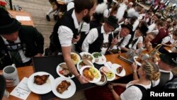 Para peserta parade Oktoberfest tampak di sebuah tenda dalam perayaan festival bir terbesar di dunia, yang digelar di Munich, Jerman, 23 September 2018.