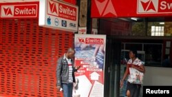 FILE - A man checks his mobile phone outside an internet cafe in Harare, Zimbabwe, January 21, 2019. 