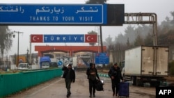 People carrying their belongings cross into to Syria from Turkey through the Kassab crossing on Dec. 27, 2024. 