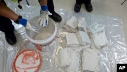 In this undated recent photo provided by the Australian Federal Police, an investigator removes packages of the methamphetamine drug from containers in Sydney. 