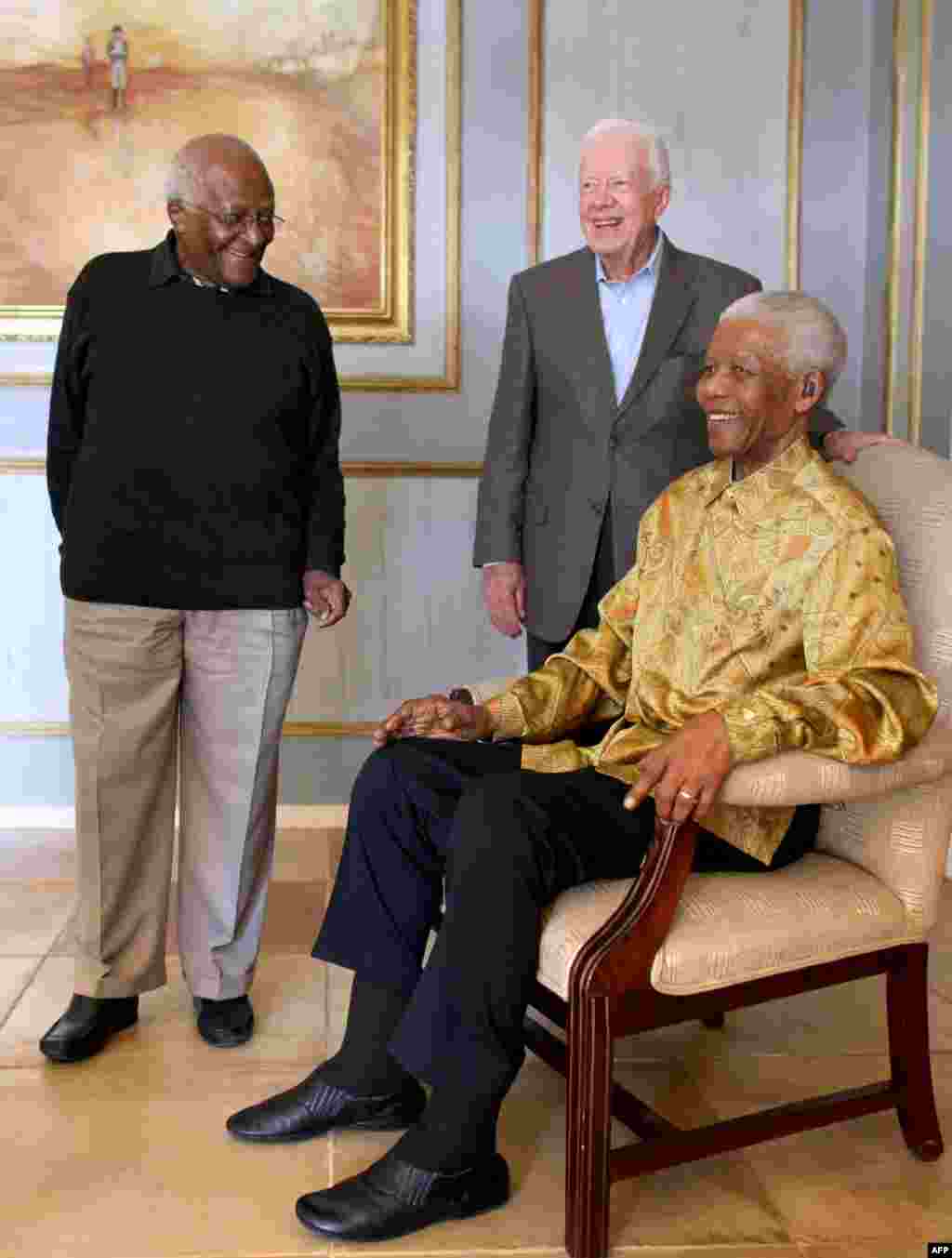 L'archevêque sud-africain Desmond Tutu (à g) et Jimmy Carter posent avec l'ex président sud-africain Nelson Mandela (assis). (Jeff Moore / AFP)