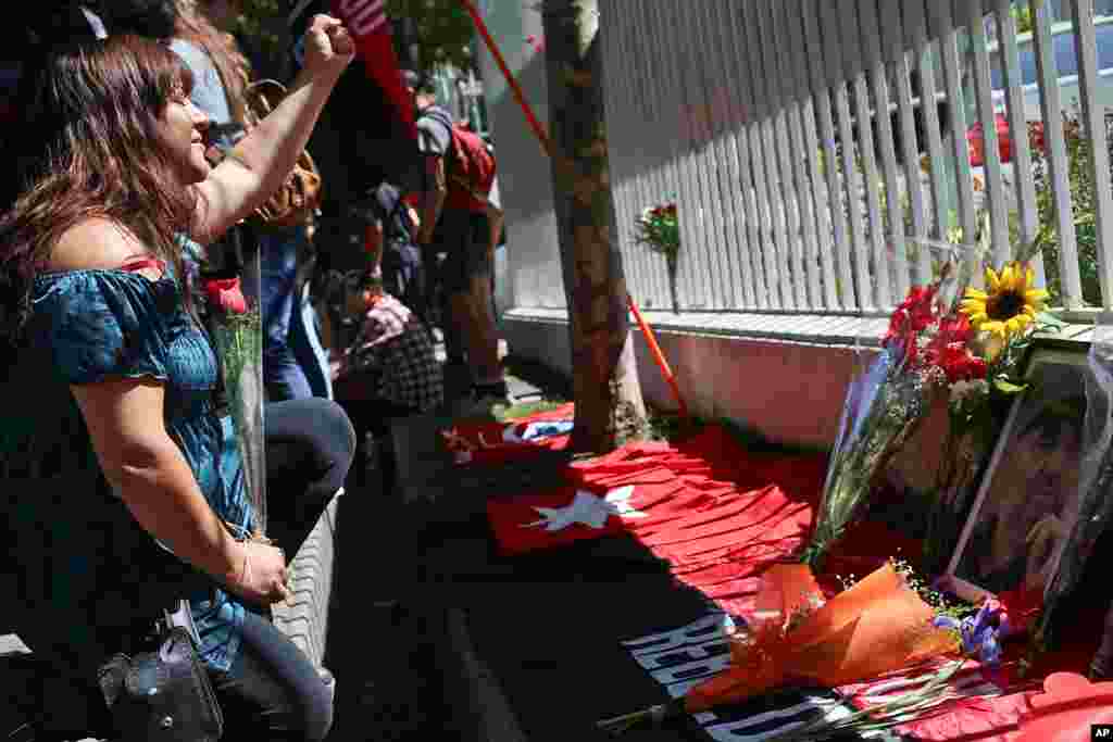 Una mujer levanta el puño ante una foto de Fidel Castro después de colocar una flor en la embajada de Cuba en Santiago, Chile, el sábado 26 de noviembre de 2016.