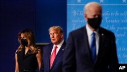 First lady Melania Trump and President Donald Trump, center, remain on stage as Democratic presidential candidate former Vice President Joe Biden walks away at the end of the final presidential debate Thursday, Oct. 22, 2020, in Nashville, Tenn.