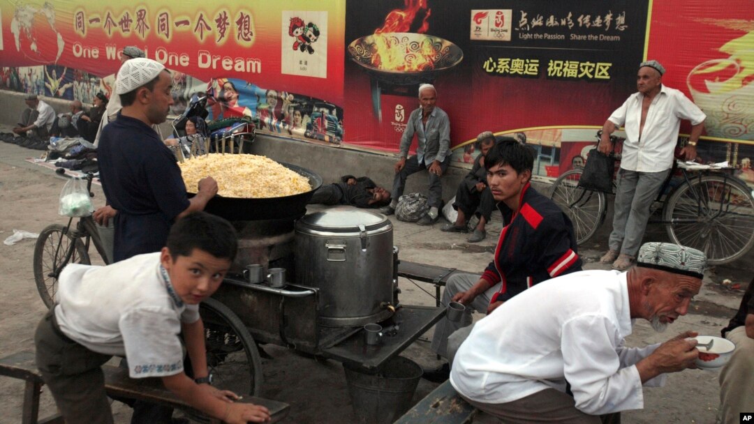 ARSIP – Dalam foto yang diambil tanggal 6 Agustus 2008 ini, warga Uighur tampak sedang beristirahat dekat warung makanan dan papan iklan Olympiade Beijing di Kashgar yang terletak di Xinjiang, provinsi China yang terletak di bagian barat (foto: AP Photo/Ng Han Guan, Arsip)