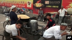 FILE - Uighurs rest near a food stall and Beijing Olympic Games billboards in Kashgar in China's western Xinjiang province, Aug. 6, 2008. Human Rights Watch said Tuesday, May 16, 2017, that China appears to be laying the groundwork for the mass collection of DNA samples from residents in a restive region with a large Muslim population.