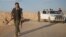 A female member of the Sinjar Resistance Units (YBS), a militia affiliated with the Kurdistan Workers' Party (PKK), carries a sniper and an AK-47 rifle in the village of Umm al-Dhiban, northern Iraq, April 29, 2016.