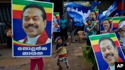 Supporters of Sri Lanka's former president and parliamentary candidate Mahinda Rajapaksa display his posters to mark conclusion of voting in Colombo, Sri Lanka, Aug. 17, 2015