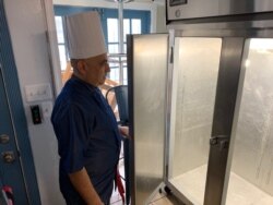 Chef Velazquez looks into an empty refrigerator that use to be full of meals he supplied to schools and day care centers. (Chris Simkins/VOA)