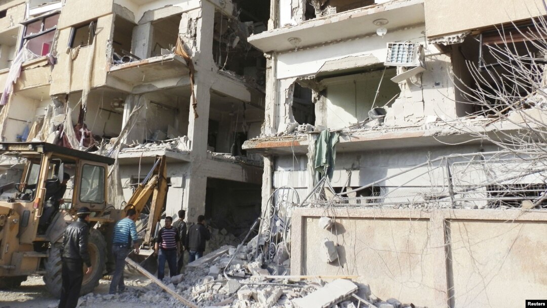 Warga berjalan di dekat bangunan yang hancur pasca serangan pesawat tempur Suriah dari pasukan pendukung Presiden Bashar al-Assad (Foto: dok). Paukan pemerintah Suriah terus menggempur wilayah di sekitar Damaskus untuk mencegah pemberontak mendekati ibukota (3/12).
