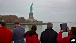 FILE - Tourists view the Statue of Liberty during a ferry ride to Liberty Island in New York, Nov. 5, 2015.