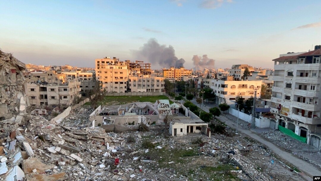 غزہ شہر میں لی گئی ایک تصویر میں 20 فروری 2024 کو اسرائیل اور فلسطینی عسکریت پسند گروپ حماس کے درمیان جاری لڑائی کے دوران، تباہ شدہ عمارتوں کا ملبہ اور پس منظر میں دھواں اٹھتے دکھایا گیا ہے۔ (تصویر اے ایف پی)