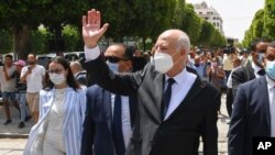 FILE - Tunisian President Kais Saied waves to bystanders as he strolls along the Avenue Habib Bourguiba in Tunis, Aug. 1, 2021.