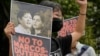 FILE - A protester holds a photo bearing the photos of the late dictator's son, Ferdinand Marcos Jr., left, and Davao city Mayor Sara Duterte during a protest outside the Commission on Human Rights in Quezon city, Philippines, Nov. 14, 2021.