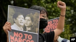 FILE - A protester holds a photo bearing the photos of the late dictator's son, Ferdinand Marcos Jr., left, and Davao city Mayor Sara Duterte during a protest outside the Commission on Human Rights in Quezon city, Philippines, Nov. 14, 2021.