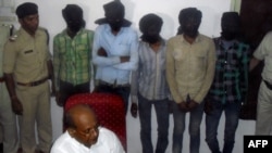 Indian Deputy Inspector General DK Arya (C) sits in front of five hooded suspects during a press meeting in Datia, about 75 kms from Gwalior in central Madhya Pradesh state, March 17, 2013. 