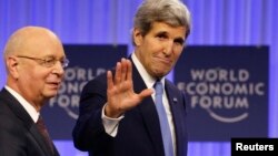 El secretario John Kerry saluda a su llegada a la reunión del Foro de Davos, acompañado de su presidente, Klaus Schwab.