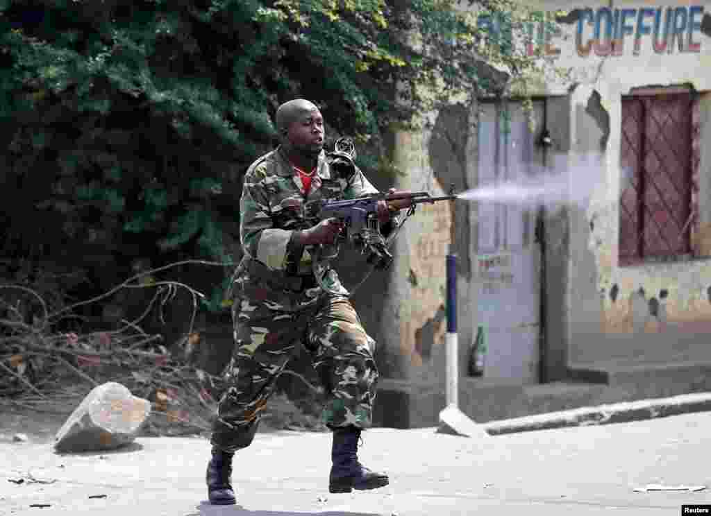 Um soldado dispara um AK-47 durante um protesto contra o presidente Pierre Nkurunziza e sua tentativa para um terceiro mandato, em Bujumbura, Burundi. &nbsp;