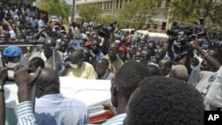 Civilians carry the body of a slain police officer to an ambulance after the killing of South Sudan's Minister for Rural Development and Cooperatives Jimmy Lemi Milla at the ministry compound in Juba February 9, 2011