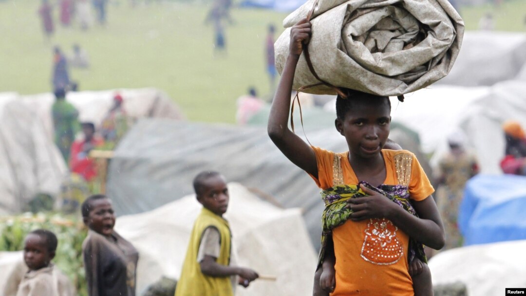 A newly arrived refugee from the Democratic Republic of Congo carries her belongings at a makeshift refugee camp at Bunagana near Kisoro town in Uganda, May 15, 2012. 