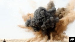 A rebel holds his ears as a bomb launched by a Libyan air force jet loyal to Libya's leader Muammar Gaddafi explodes in the desert near Brega, March 2, 2011