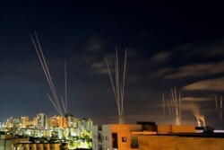 FILE - Streaks of light are seen as rockets are launched from the Gaza Strip towards central Israel as seen from Ashkelon, Israel