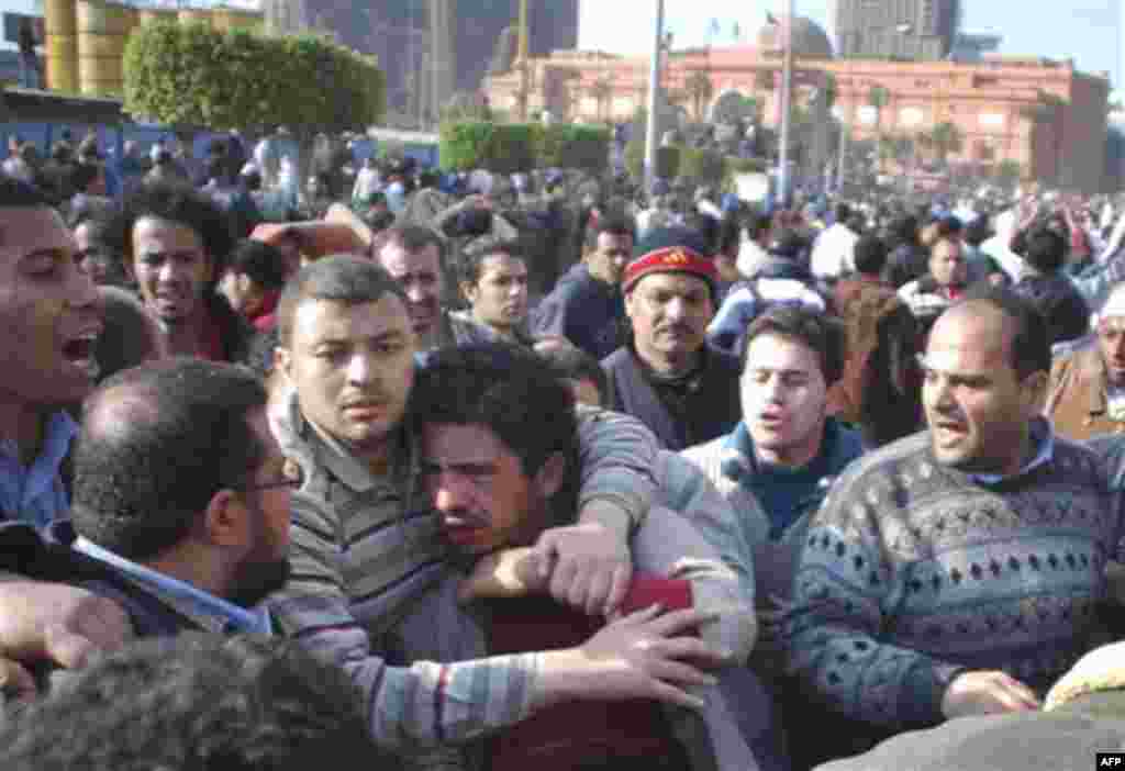 A supporter of President Hosni Mubarak, centre, is caught by anti anti-Mubarak protesters in Cairo, Egypt, Wednesday, Feb.2, 2011. Several thousand supporters of President Hosni Mubarak, including some riding horses and camels and wielding whips, clashed