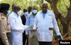 Kenya's Interior Minister Kithure Kindiki talks to forensic experts and homicide detectives from the Directorate of Criminal Investigations, as they prepare to exhume bodies of starvation cult victims, in Kilifi, May 9, 2023.