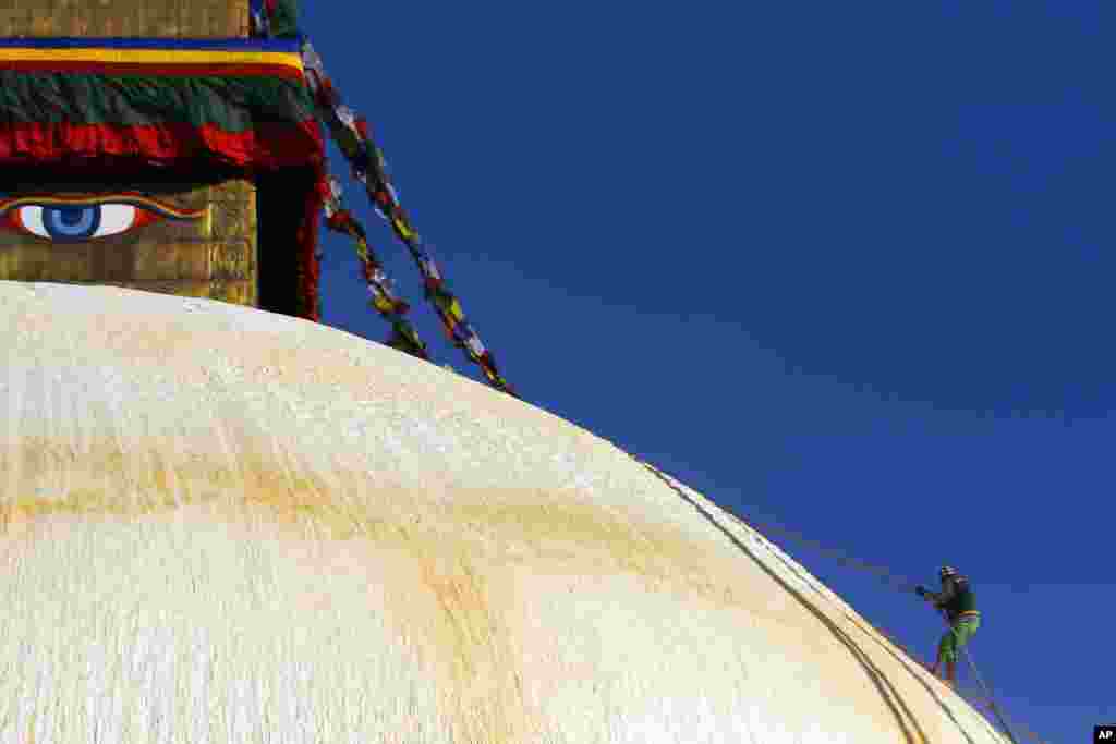 A Nepalese man climbs the Boudhanath stupa in Katmandu, a world heritage site, for renovation.