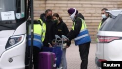 A traveler is assisted by security outside the Novotel at Heathrow Airport, as Britain introduces a hotel quarantine programme for arrivals from a "red list" of 30 countries due to the coronavirus disease (COVID-19) pandemic, in London, Feb. 25, 2021. 