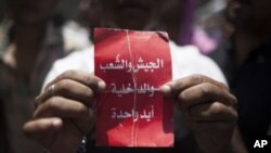 Tahrir Meydanında" ordu, halk, polis elele" yazılı kart tutan bir gösterici