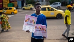 A young man sells calendars featuring Pope Francis outside the Cathedral Notre Dame du Congo in Kinshasa, Democratic Republic of the Congo, Jan. 29, 2023.