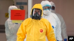 Russian President Vladimir Putin, center, wearing a protective suit enters a hall during his visit to the hospital for coronavirus patients in Kommunarka settlement, outside Moscow, Russia, March 24, 2020. 