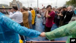 Para aktivis bergandengan tangan membentuk barikade untuk mengamankan area bagi mereka yang menghadiri sholat Jumat di Lapangan Taksim, Jumat (14/6). Para pemotres masih bertahan di taman Gezi Istanbul meskipun telah diberi peringatan terakhir untuk meninggalkan area tersebut, pasca pertemuan dengan PM Erdogan, Kamis malam.